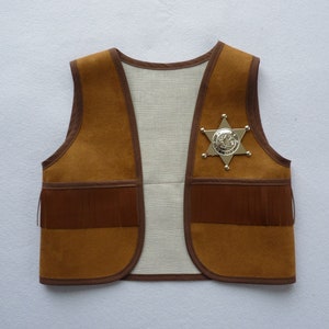May include: A brown suede vest with fringe detailing and a gold sheriff's star badge.