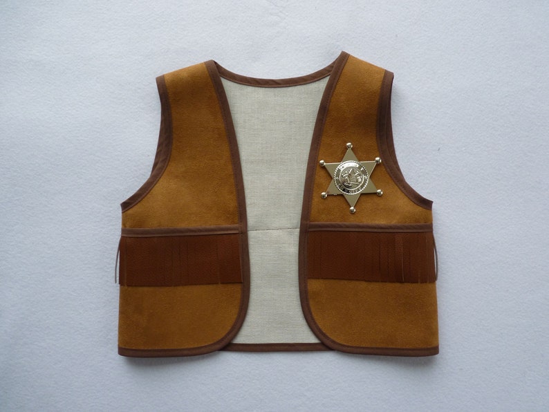 May include: A brown suede vest with fringe detailing and a gold sheriff's star badge.