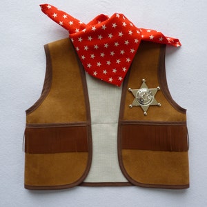 May include: A brown suede vest with fringe detailing, a silver sheriff's badge, and a red bandana with white stars.