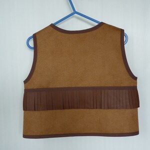 May include: Brown suede vest with a brown fringe trim. The vest has a round neckline and sleeveless design.