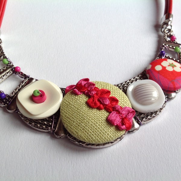 Collier plastron "Vive le printemps!" Cabochon artisanaux recouverts de tissu,boutons vintage ,perles sur support en métal argenté.