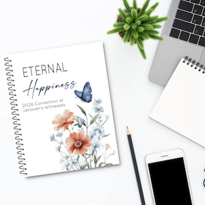Könnte beinhalten: Ein weißes Spiralnotizbuch mit den Worten "ETERNAL Happiness" und "2026 Convention of Jehovah's Witnesses" auf dem Einband. Der Einband zeigt Aquarellillustrationen von Blumen und einem Schmetterling. Ein Laptop, ein Smartphone und ein Bleistift sind ebenfalls sichtbar.
