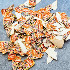 Pode incluir: Uma coleção de etiquetas de papel vintage espalhadas sobre uma superfície cinza. As etiquetas são laranja com desenhos florais e o texto "ESSENCE H Payan Grasse Paris". Algumas etiquetas têm formato de escudo, outras são irregulares.