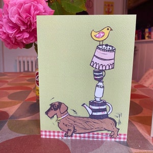 Teckel à poil dur, chien en équilibre, théière, gâteau, tasse de lait et oiseau