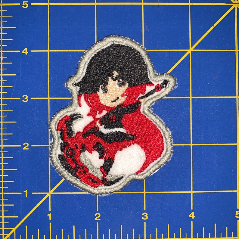 May include: Embroidered patch featuring a red-haired anime character with black hair and a red and white outfit. The character is holding a sword and has a determined expression.