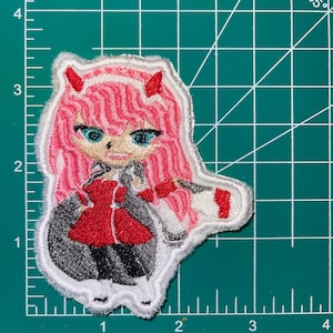 Op de afbeelding: Geborduurde patch met een anime-personage met roze haar, rode hoorns en een rood jasje. Het personage draagt een witte kraag en een witte rok. De patch is omgeven door een witte rand.