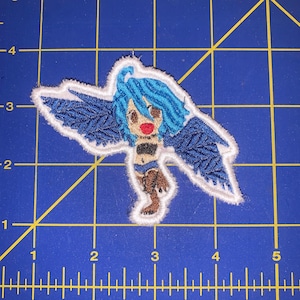 May include: Embroidered patch featuring a blue-haired anime character with wings. The character is wearing a brown and black outfit and has a red nose.
