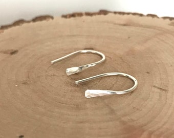 May include: A pair of silver hoop earrings with a hammered texture. The earrings are simple and elegant, and would make a great gift.