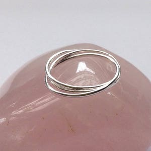 May include: Three silver rings stacked on top of each other on a pink stone.