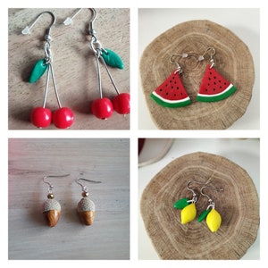 Peut inclure: Quatre paires de boucles d'oreilles pendantes avec des motifs de fruits. La première paire est des cerises rouges avec des feuilles vertes. La deuxième paire est des tranches de pastèque. La troisième paire est des glands. La quatrième paire est des citrons avec des feuilles vertes.