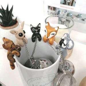 Può includere: Infusori da tè a tema animale. Ogni infusore presenta una piccola e dettagliata figurina di animale in vari colori, tra cui un gatto nero e una volpe marrone. Le figurine sono appese a una catena d'argento attaccata a una sfera da tè in acciaio inossidabile.