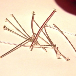 May include: A pile of silver-toned head pins, used for jewelry making and crafting.