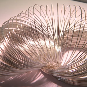 Op de afbeelding: Een zilveren metalen slinky-speelgoed, een klassiek veer-speelgoed dat kan worden uitgerekt en samengedrukt.
