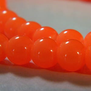 Könnte beinhalten: Eine Reihe von leuchtend orangefarbenen runden Perlen. Die Perlen sind glatt und glänzend.