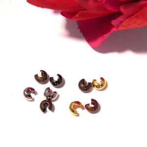 Könnte beinhalten: Sortiment an Metall-Quetschperlen in Gold, Silber und Bronze. Die Perlen sind klein und rund mit einer Quetschöffnung.