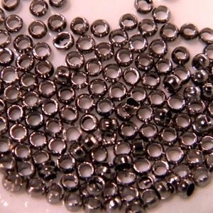 May include: A large quantity of small, silver-colored metal rings. The rings are all the same size and shape, and they are arranged in a random pattern.