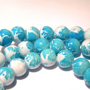 May include: A strand of white and blue round beads with a marbled effect. The beads are made of glass and have a glossy finish.