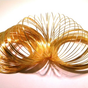 Op de afbeelding: Een gouden metalen slinky-speelgoed, gemaakt van veel in elkaar grijpende draadspiralen. De slinky is uitgerekt en lijkt uit veel afzonderlijke ringen te bestaan.