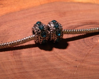 May include: Two silver charm beads with blue rhinestones on a silver chain.