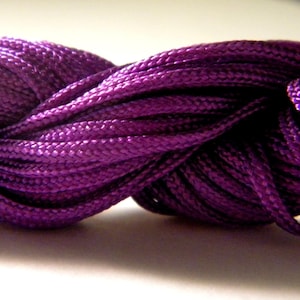 Peut inclure: Gros plan sur un cordon violet foncé, torsadé et noué, montrant la texture du tissu.