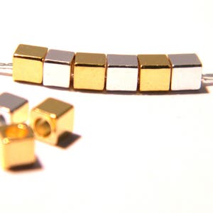 May include: A gold and silver chain with square beads. The beads are alternating gold and silver.