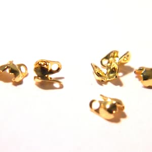 May include: Six gold-toned metal clasps for jewelry making. The clasps are small and have a rounded shape.