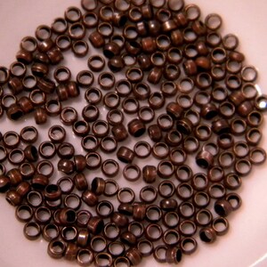 May include: A large quantity of small, copper-colored metal rings. The rings are all the same size and shape, and they are arranged in a random pattern.