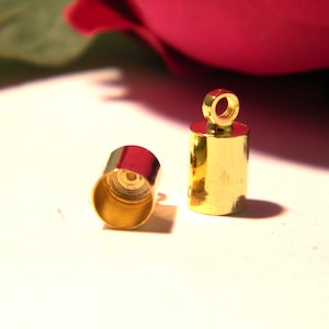 May include: Two gold-colored metal end caps for cord or string. One end cap has a loop for attaching to a cord or string.