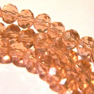 Peut inclure: Un brin de perles de verre facettées de couleur pêche clair. Les perles sont rondes et ont une finition légèrement irisée.