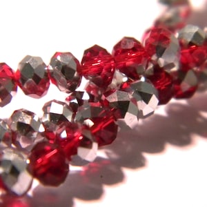 Peut inclure: Un brin de perles de cristal rouge et argent. Les perles sont facettées et ont une finition brillante.