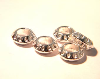 Pode incluir: Cinco contas de metal prateado com um padrão decorativo ao redor da borda. As contas são projetadas para serem usadas na fabricação de joias.