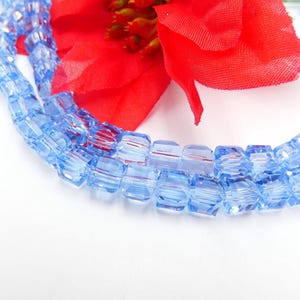 Puede incluir: Una hebra de cuentas cuadradas de vidrio azul claro. Las cuentas son facetadas y tienen una apariencia translúcida.