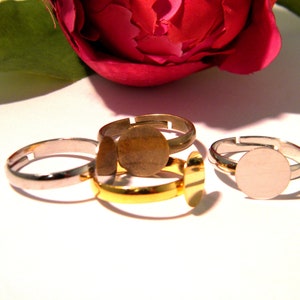 May include: Three adjustable ring blanks with round metal settings. The rings are silver, gold, and bronze.