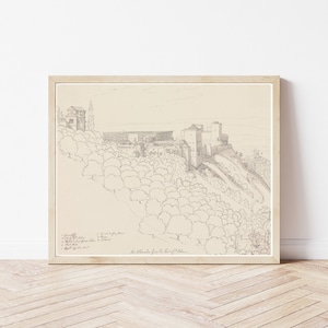 May include: A black and white line drawing of a castle on a hill. The drawing is framed in a light wood frame. The drawing is titled "The Alhambra from the East of the City."