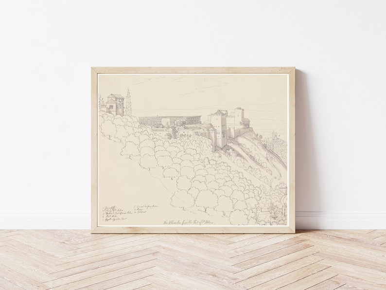 May include: A black and white line drawing of a castle on a hill. The drawing is framed in a light wood frame. The drawing is titled "The Alhambra from the East of the City."