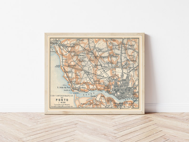 Peut inclure: Une carte ancienne de Porto, au Portugal, imprim&eacute;e en encre noire, brune et bleue sur un fond cr&egrave;me. La carte montre les rues de la ville, ses monuments et ses environs. Le titre "CIRCUMVISINHAN&Ccedil;AS DO PORTO" est imprim&eacute; en bas de la carte.