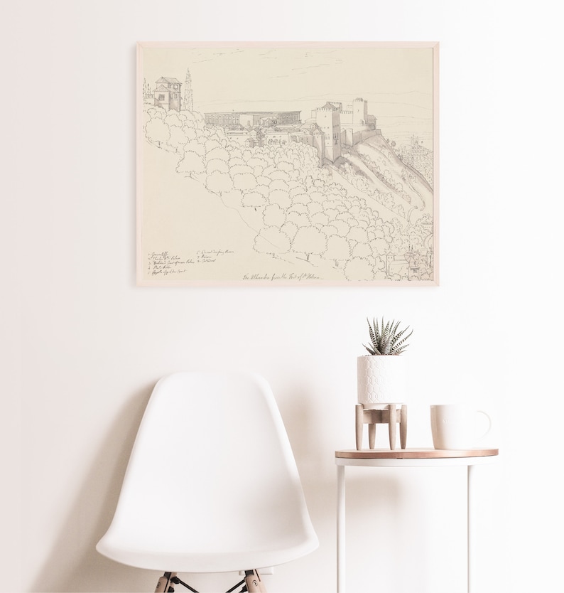May include: A black and white line drawing of a castle on a hill with trees. The drawing is framed and hanging on a white wall. The text "The Alcazaba from the East of Malaga" is written below the drawing.