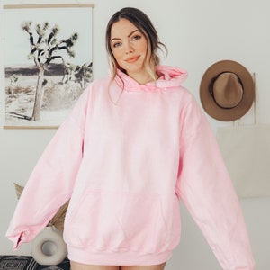 Puede incluir: Una sudadera con capucha rosa claro con un bolsillo delantero y una capucha con cord&oacute;n. La sudadera est&aacute; hecha de un material suave y es de color liso. La sudadera con capucha es de estilo casual y es adecuada para el uso diario.