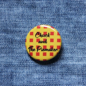 May include: A yellow and red button with a checkered pattern. The button says "Chuck and The Piemaker" in black text.