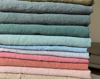 May include: A stack of 14 linen fabric swatches in various colors, including green, blue, pink, beige, and white.