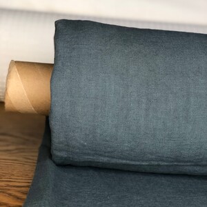 May include: A roll of teal linen fabric. The fabric is folded and rolled up, with a cardboard tube inside.