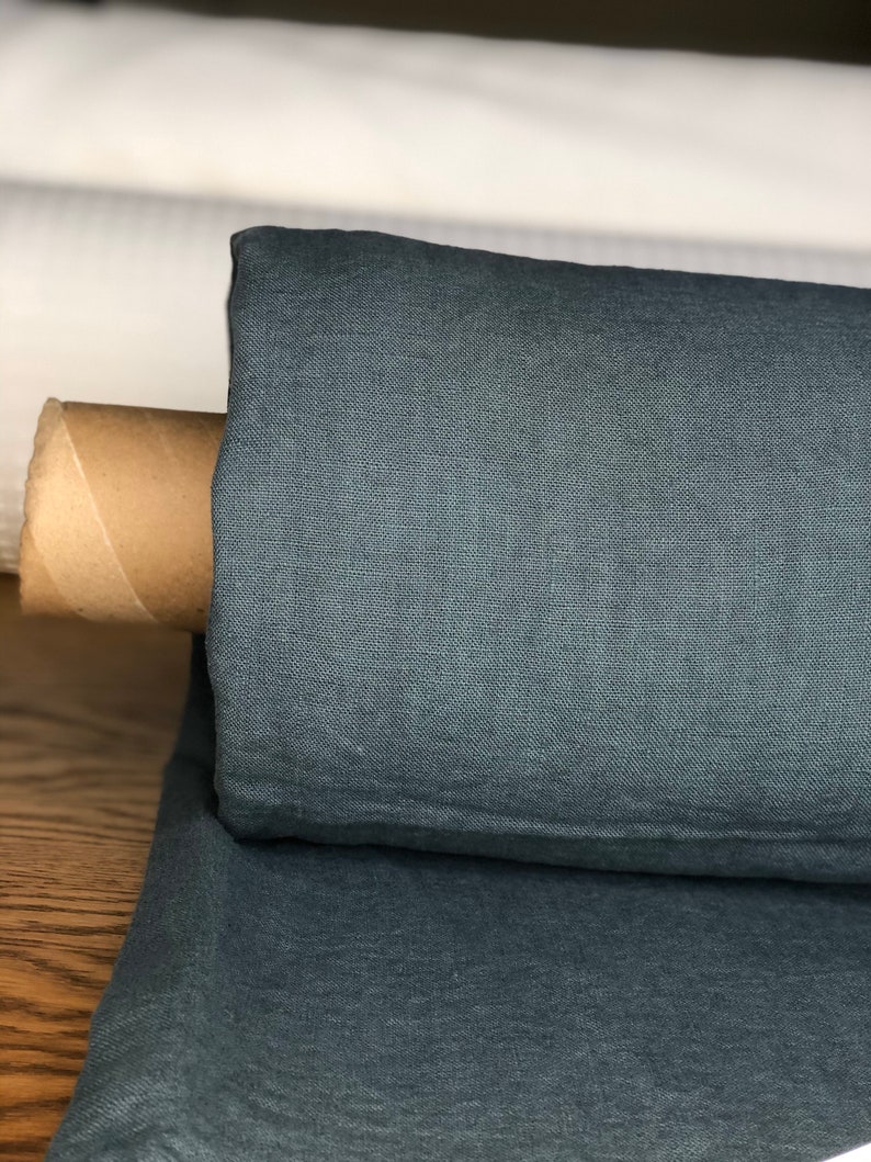 May include: A roll of teal linen fabric. The fabric is folded and rolled up, with a cardboard tube inside.