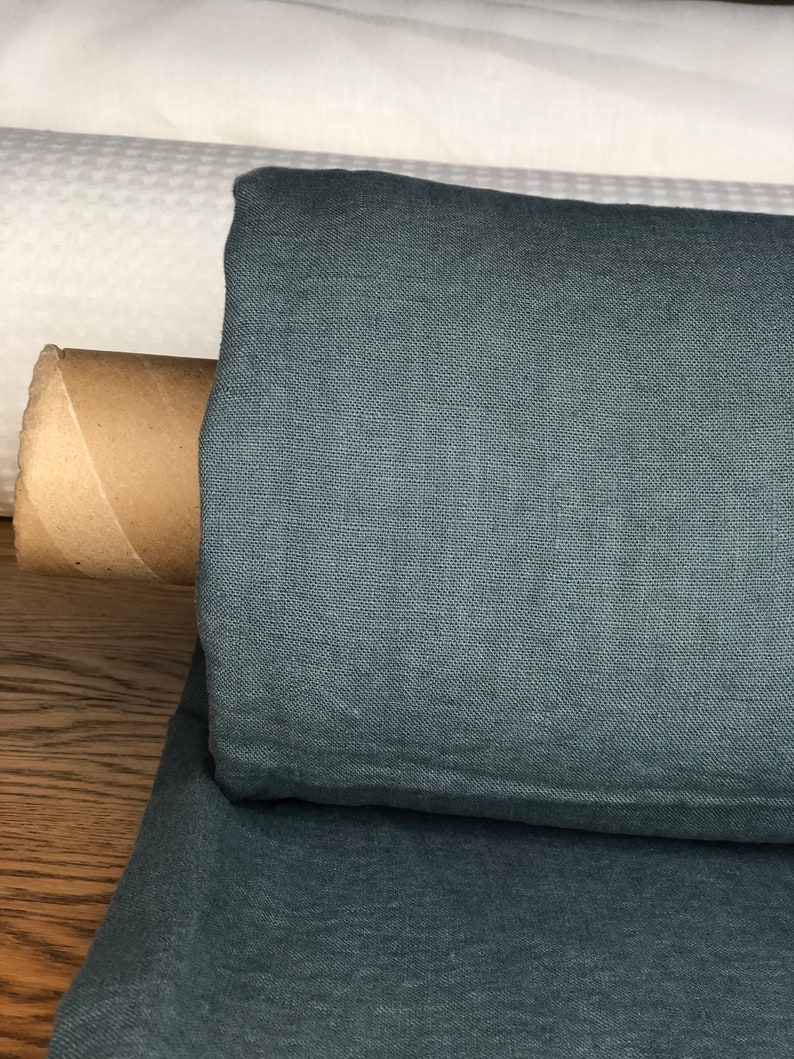 May include: A roll of dark teal linen fabric. The fabric has a textured weave and is folded in half.