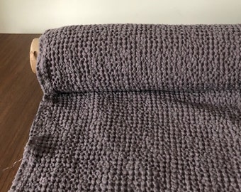 May include: A roll of dark gray waffle weave fabric. The fabric has a textured, waffle-like pattern.