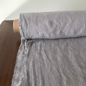 May include: A roll of light gray linen fabric with a raw edge. The fabric is soft and has a natural texture.