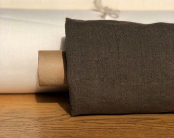 May include: A roll of brown linen fabric is displayed on a wooden surface. The fabric is rolled up and secured with a cardboard tube. The fabric has a subtle texture and a slightly darker shade of brown.