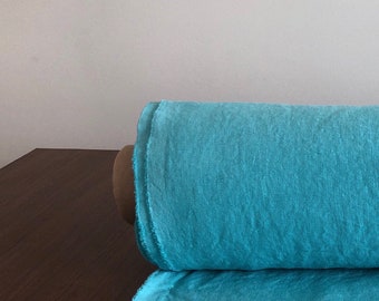 May include: A roll of teal linen fabric with a slightly frayed edge.