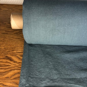 May include: A roll of blue linen fabric. The fabric has a textured, woven look.
