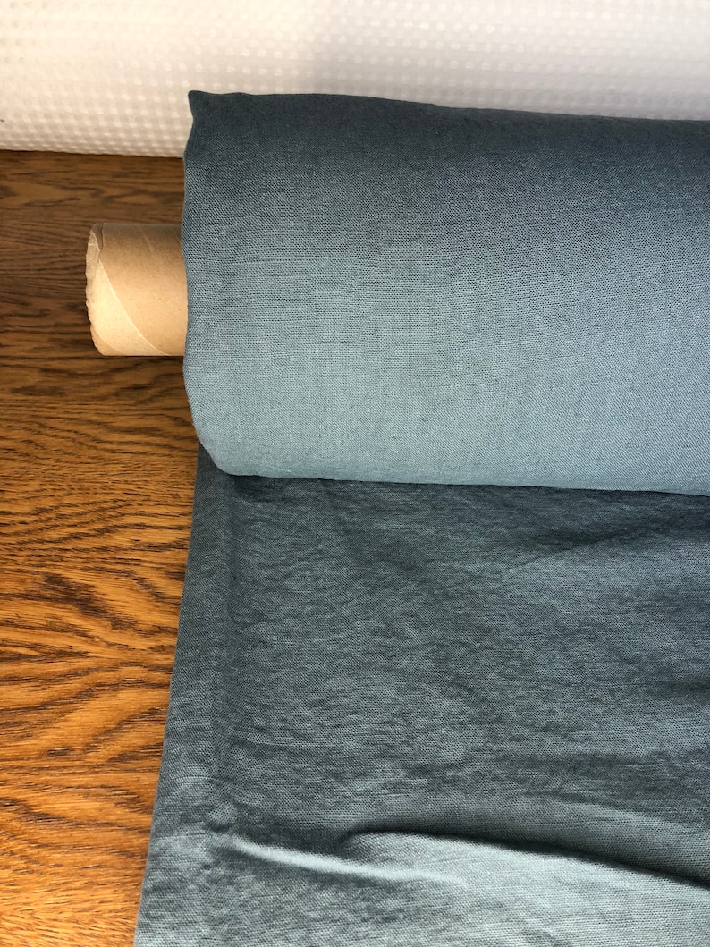 May include: A roll of blue linen fabric. The fabric has a textured, woven look.