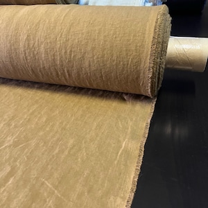 May include: A roll of brown linen fabric with a raw edge. The fabric is rolled up and tied with a brown cord.